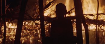 Movie still from “The Thin Red Line” (1998), directed by Terrence Malick – A person sitting in front of a fire; Close Up shot, Over the shoulder angle