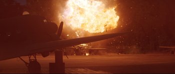 Movie still from “The Thin Red Line” (1998), directed by Terrence Malick – An explosion is seen in the background of this picture; Wide shot, Low angle