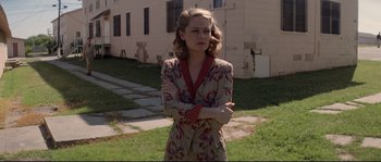 Movie still from “The Thin Red Line” (1998), directed by Terrence Malick – A woman in a robe standing in front of a building; Medium shot, Low angle