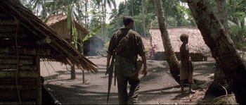 Movie still from “The Thin Red Line” (1998), directed by Terrence Malick – A man walking through a dirt field with a rifle; Wide shot, High angle