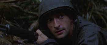 Movie still from “The Thin Red Line” (1998), directed by Terrence Malick – A man in a helmet is holding a rifle; Close Up shot, High angle