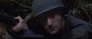 Movie still from “The Thin Red Line” (1998), directed by Terrence Malick – A man wearing a helmet looking at the camera; Close Up shot, Low angle