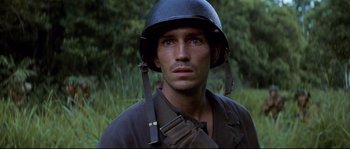 Movie still from “The Thin Red Line” (1998), directed by Terrence Malick – A man wearing a helmet and holding a rifle; Close Up shot, Over the shoulder angle