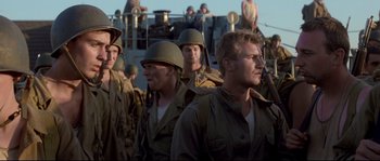 Movie still from “The Thin Red Line” (1998), directed by Terrence Malick – A group of men standing next to each other; Medium shot, Low angle