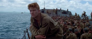 Movie still from “The Thin Red Line” (1998), directed by Terrence Malick – A man with a gun on a boat; Medium shot, Low angle