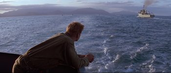 Movie still from “The Thin Red Line” (1998), directed by Terrence Malick – A man sitting on the edge of a boat in the ocean; Wide shot, High angle