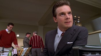 Movie still from “The Truman Show” (1998), directed by Peter Weir – A man in a suit and tie sitting at a table; Close Up shot, Low angle