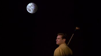 Movie still from “The Truman Show” (1998), directed by Peter Weir – A man holding a stick standing in front of the moon; Medium shot, Low angle