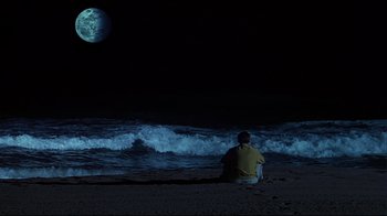 Movie still from “The Truman Show” (1998), directed by Peter Weir – A man sitting on the beach looking at the moon; Extreme Wide shot, High angle