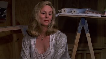 Movie still from “The Truman Show” (1998), directed by Peter Weir – A woman in a white robe sitting in front of a shelf; Close Up shot, Over the shoulder angle