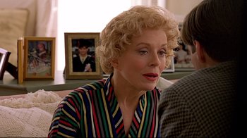 Movie still from “The Truman Show” (1998), directed by Peter Weir – An older woman with blonde curly hair wearing a striped shirt; Close Up shot, Over the shoulder angle