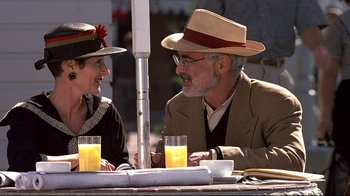 Movie still from “The Truman Show” (1998), directed by Peter Weir – An older man and woman sitting at an outdoor table; Close Up shot, Low angle