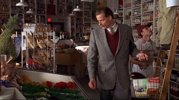 Movie still from “The Truman Show” (1998), directed by Peter Weir – A man in a suit and tie in a grocery store; Medium shot, Over the shoulder angle