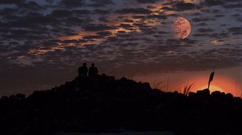 Movie still from “The Truman Show” (1998), directed by Peter Weir – Two people sitting on top of a hill at sunset; Extreme Wide shot, Low angle