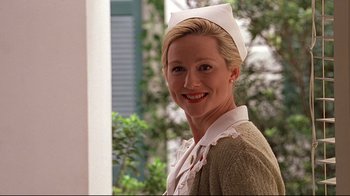 Movie still from “The Truman Show” (1998), directed by Peter Weir – A woman wearing a nurse's uniform and smiling for the camera; Close Up shot, Low angle