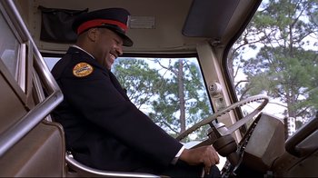 Movie still from “The Truman Show” (1998), directed by Peter Weir – A man in a uniform driving a car; Medium shot, Low angle