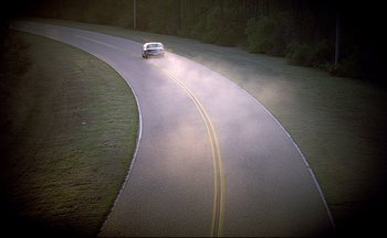Movie still from “The Truman Show” (1998), directed by Peter Weir – A car driving down a curvy road in the middle of the night; Extreme Wide shot, High angle