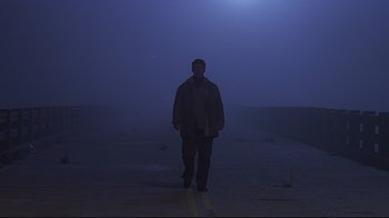 Movie still from “The Truman Show” (1998), directed by Peter Weir – A man standing in the middle of a road in the fog; Wide shot, Low angle