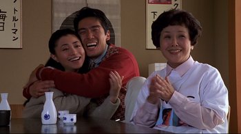 Movie still from “The Truman Show” (1998), directed by Peter Weir – Two women and a man sitting at a table; Medium shot, Over the shoulder angle