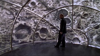 Movie still from “The Truman Show” (1998), directed by Peter Weir – A man standing in front of an image of the moon; Wide shot, High angle