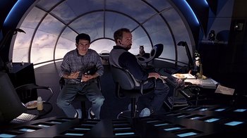 Movie still from “The Truman Show” (1998), directed by Peter Weir – Two men are sitting in a room in a space ship; Wide shot, High angle