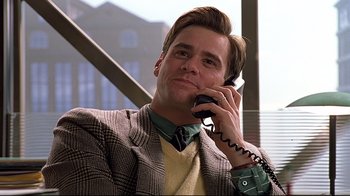 Movie still from “The Truman Show” (1998), directed by Peter Weir – A man talking on a cell phone while wearing a suit; Medium shot, Low angle