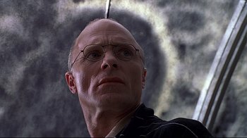 Movie still from “The Truman Show” (1998), directed by Peter Weir – A bald man with glasses looking up into the sky; Close Up shot, Low angle