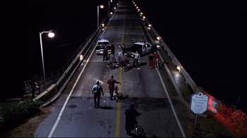 Movie still from “The Truman Show” (1998), directed by Peter Weir – A group of people standing on a bridge at night; Extreme Wide shot, High angle