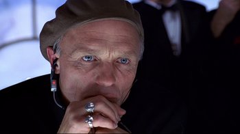 Movie still from “The Truman Show” (1998), directed by Peter Weir – An older man wearing a hat and holding a ring in front of his face; Close Up shot, Low angle