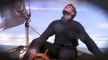 Movie still from “The Truman Show” (1998), directed by Peter Weir – A man sitting on the deck of a boat with his eyes closed; Medium shot, Low angle