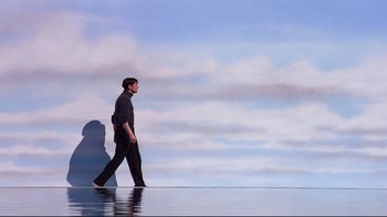 Movie still from “The Truman Show” (1998), directed by Peter Weir – A man is walking on the water in front of a mountain; Extreme Wide shot, Low angle