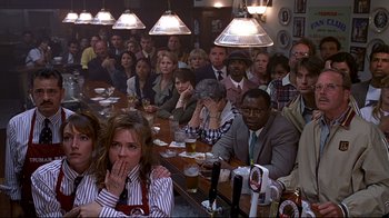 Movie still from “The Truman Show” (1998), directed by Peter Weir – A group of people sitting at a table with beers; Medium shot, High angle
