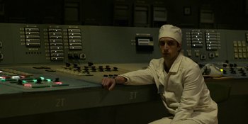Movie still from “Chernobyl” (2019), directed by Johan Renck – A man in a white lab coat sitting in front of a control panel; Medium shot, Low angle