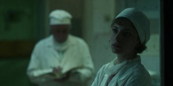 Movie still from “Chernobyl” (2019), directed by Johan Renck – A woman in a white lab coat and a man in white lab coats; Medium shot, Over the shoulder angle