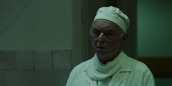 Movie still from “Chernobyl” (2019), directed by Johan Renck – An old man in a white lab coat and hat; Close Up shot, Over the shoulder angle