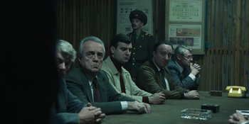 Movie still from “Chernobyl” (2019), directed by Johan Renck – A group of men sitting at a table in a room; Medium shot, Over the shoulder angle