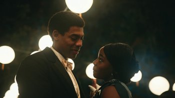 Movie still from “The Underground Railroad” (2021), directed by Barry Jenkins – A man and a woman standing next to each other in front of lights; Close Up shot, Over the shoulder angle