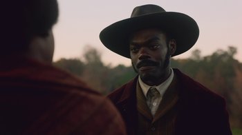 Movie still from “The Underground Railroad” (2021), directed by Barry Jenkins – A man wearing a hat and a jacket; Close Up shot, Over the shoulder angle