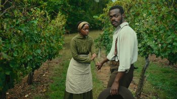Movie still from “The Underground Railroad” (2021), directed by Barry Jenkins – A man and a woman standing next to each other in a field; Medium shot, High angle