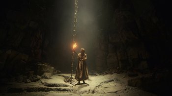 Movie still from “The Underground Railroad” (2021), directed by Barry Jenkins – A person standing in a cave holding a light; Wide shot, Low angle