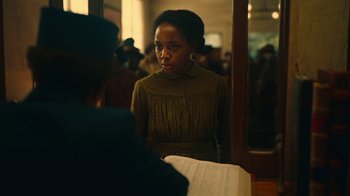 Movie still from “The Underground Railroad” (2021), directed by Barry Jenkins – A woman in a brown dress looking at a man in a black suit; Medium shot, Over the shoulder angle
