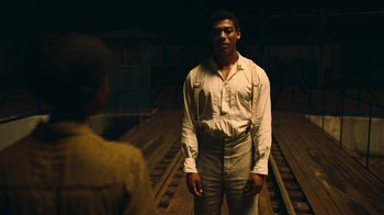 Movie still from “The Underground Railroad” (2021), directed by Barry Jenkins – A man standing on train tracks next to a woman; Medium shot, Over the shoulder angle