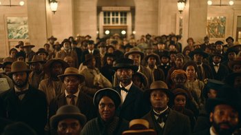 Movie still from “The Underground Railroad” (2021), directed by Barry Jenkins – A large group of people wearing hats in a building; Extreme Wide shot, High angle