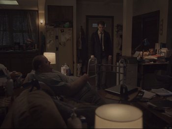 Movie still from “The Whale” (2022), directed by Darren Aronofsky – A man in a suit and tie standing in front of another man in a suit and tie; Wide shot, Over the shoulder angle