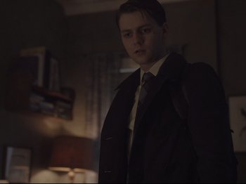 Movie still from “The Whale” (2022), directed by Darren Aronofsky – A man in a suit and tie standing next to a lamp; Medium shot, Low angle