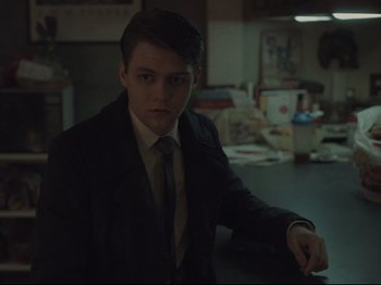 Movie still from “The Whale” (2022), directed by Darren Aronofsky – A man in a suit and tie sitting in a room; Medium shot, Over the shoulder angle