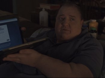 Movie still from “The Whale” (2022), directed by Darren Aronofsky – A man sitting on a couch holding a laptop; Close Up shot, Over the shoulder angle
