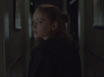 Movie still from “The Whale” (2022), directed by Darren Aronofsky – A young woman in a black jacket standing in a dark hallway; Close Up shot, Over the shoulder angle