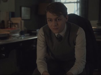 Movie still from “The Whale” (2022), directed by Darren Aronofsky – A man sitting in a chair in front of a desk; Medium shot, Over the shoulder angle