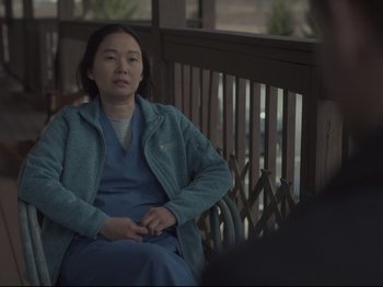 Movie still from “The Whale” (2022), directed by Darren Aronofsky – A woman sitting on top of a wooden railing; Medium shot, Over the shoulder angle